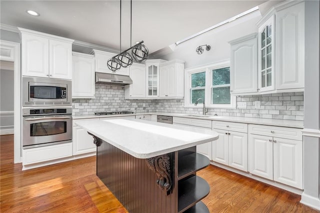 kitchen with appliances with stainless steel finishes, white cabinetry, sink, and ventilation hood