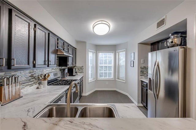 kitchen featuring backsplash, sink, light stone counters, and stainless steel appliances