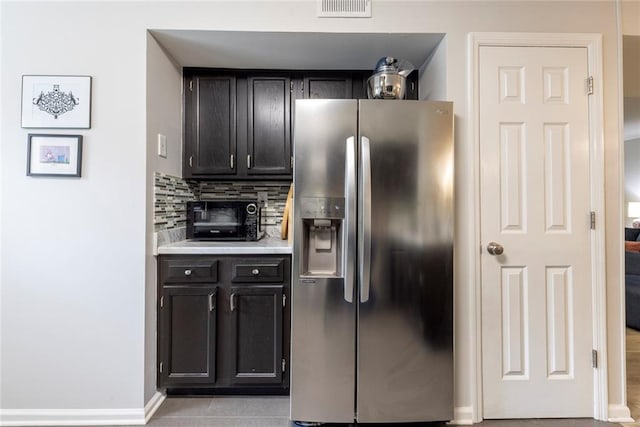 kitchen with stainless steel fridge with ice dispenser, tasteful backsplash, and light tile patterned floors