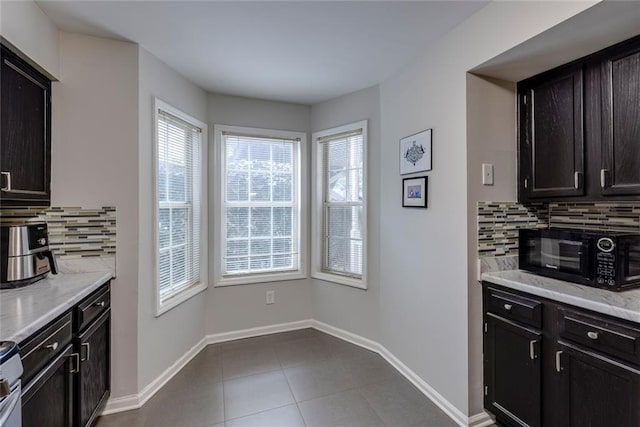 kitchen featuring decorative backsplash, dark brown cabinetry, tile patterned floors, and light stone countertops