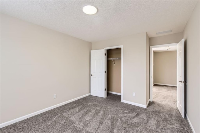 unfurnished bedroom featuring a closet, dark carpet, a textured ceiling, and baseboards