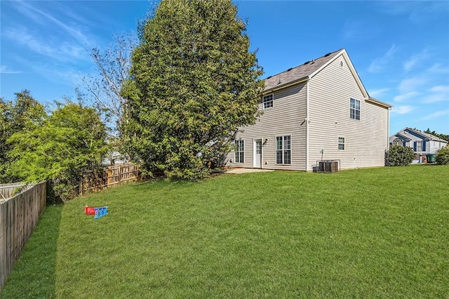 back of house with a fenced backyard, a lawn, and central air condition unit