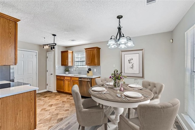 dining area featuring a textured ceiling, visible vents, baseboards, stone finish floor, and an inviting chandelier