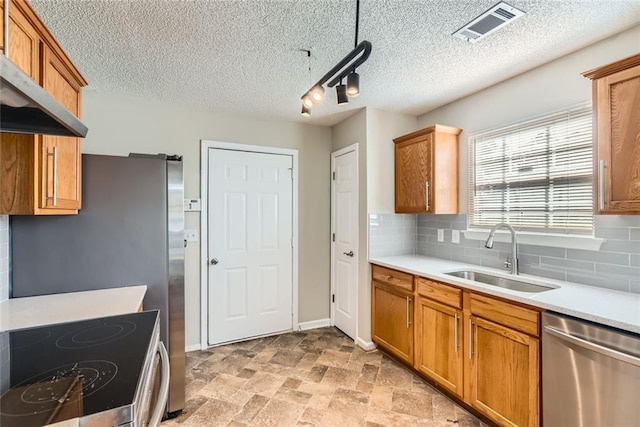 kitchen with stainless steel appliances, light countertops, visible vents, a sink, and extractor fan