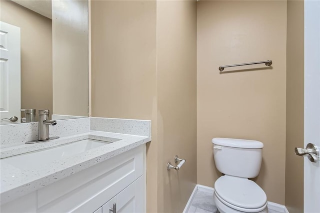 bathroom featuring toilet, baseboards, and vanity