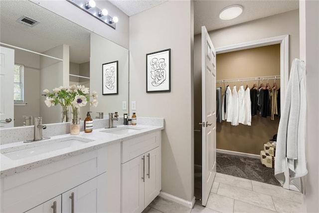 full bathroom featuring a textured ceiling, double vanity, a sink, and visible vents