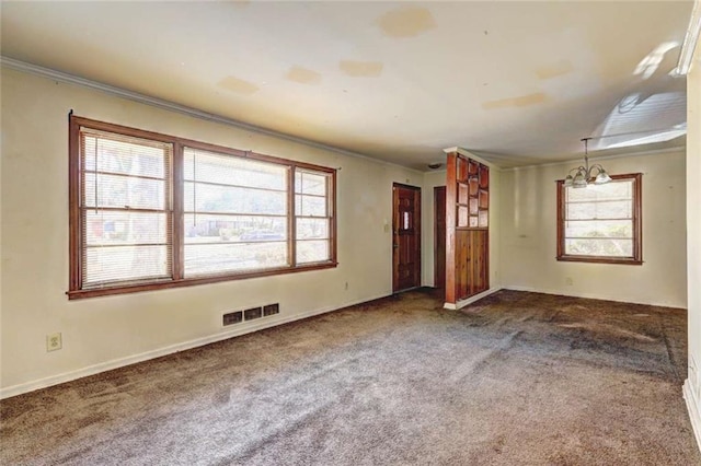 carpeted empty room featuring ornamental molding and a notable chandelier