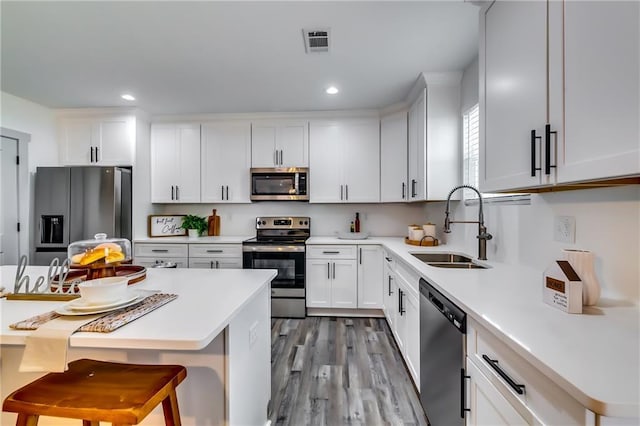 kitchen featuring visible vents, white cabinetry, stainless steel appliances, and a sink