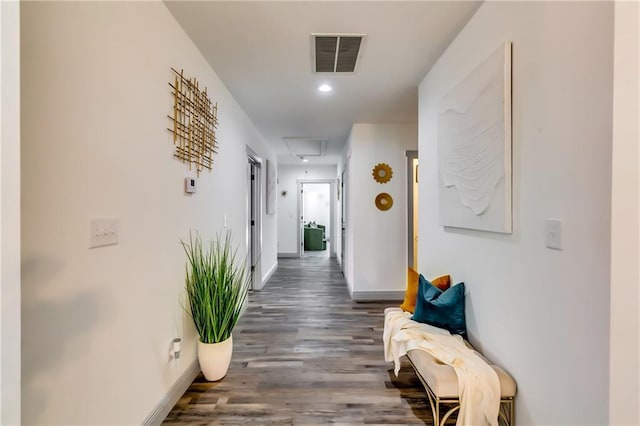 hallway with visible vents, baseboards, attic access, and dark wood-style flooring