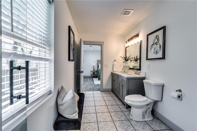 bathroom with vanity, visible vents, baseboards, tile patterned flooring, and toilet