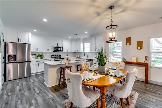 dining area with a chandelier, plenty of natural light, recessed lighting, and dark wood-type flooring