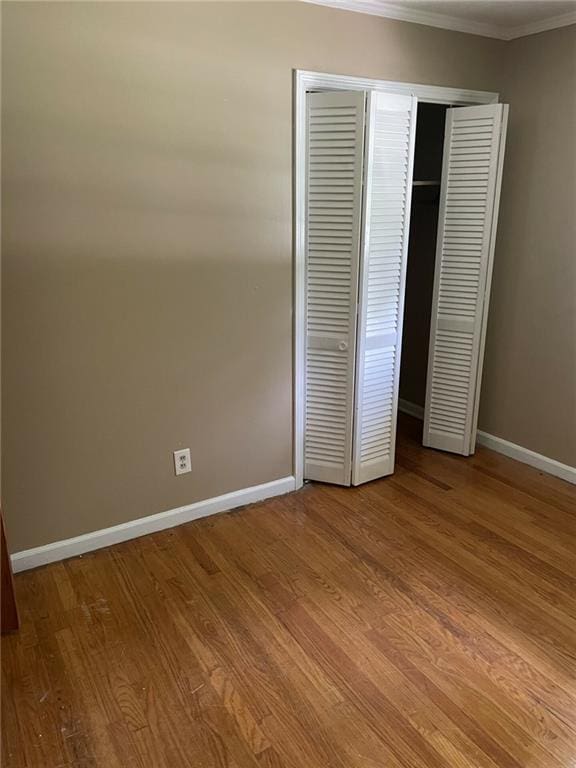 unfurnished bedroom with crown molding and hardwood / wood-style floors