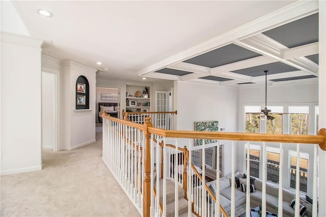 hall with beamed ceiling, crown molding, coffered ceiling, and light colored carpet