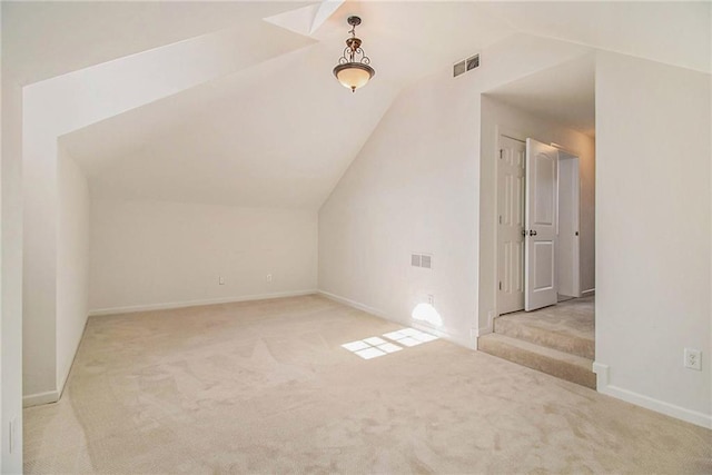 additional living space featuring vaulted ceiling and light carpet