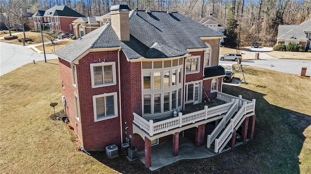 back of property with a wooden deck, central AC unit, and a lawn