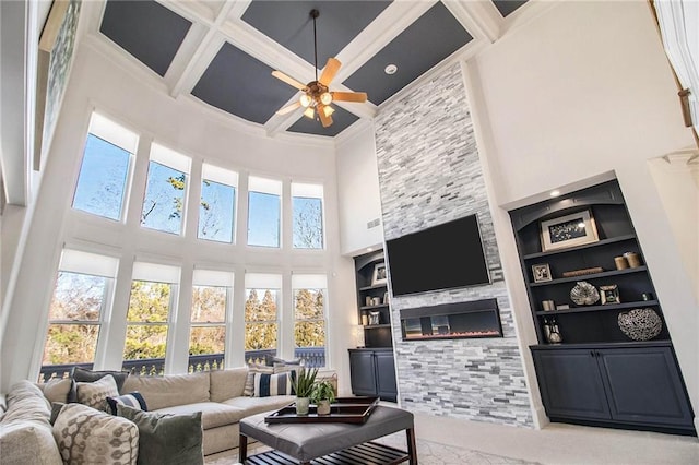 living room with crown molding, built in features, ceiling fan, coffered ceiling, and a large fireplace