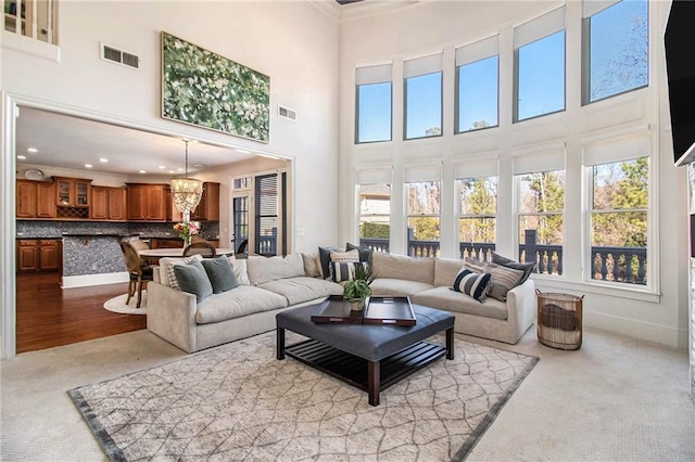 carpeted living room with a towering ceiling and a chandelier