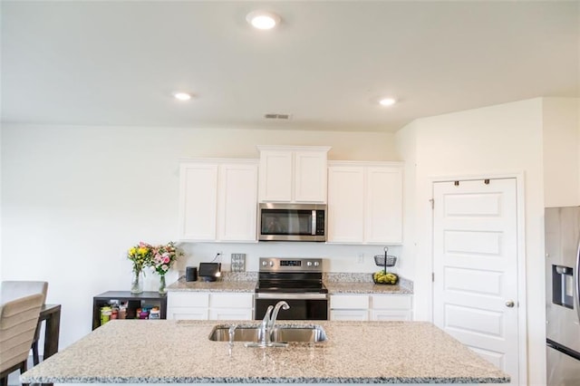2159 Redfern Rd, Dacula, GA 30019 - kitchen with appliances with stainless steel finishes, white cabinetry, a center island with sink, light stone countertops, and recessed lighting