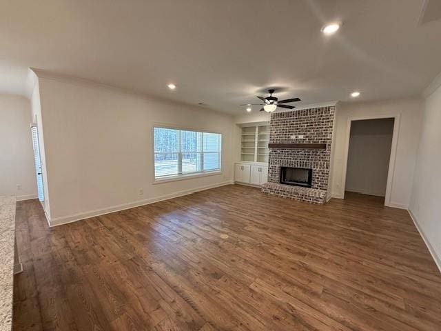unfurnished living room featuring dark wood-style floors, a fireplace, a ceiling fan, and built in features