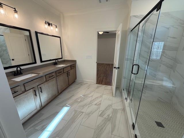 bathroom with marble finish floor, a sink, a shower stall, and double vanity