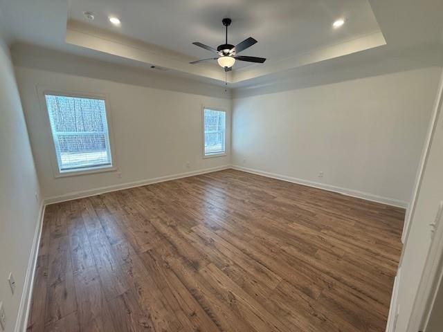 unfurnished room featuring a tray ceiling, wood finished floors, and baseboards