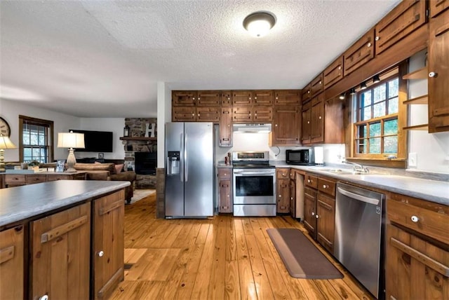 kitchen featuring a wealth of natural light, sink, stainless steel appliances, a textured ceiling, and a fireplace