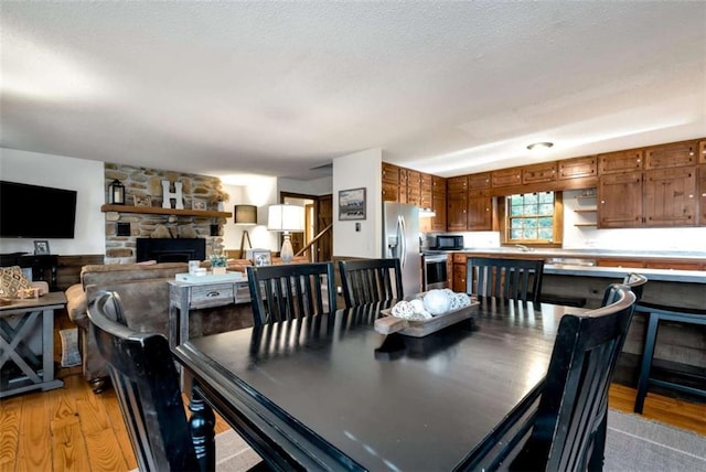 dining area featuring a fireplace, a textured ceiling, and light hardwood / wood-style flooring