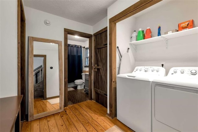 clothes washing area featuring washer and dryer, a textured ceiling, and light hardwood / wood-style floors