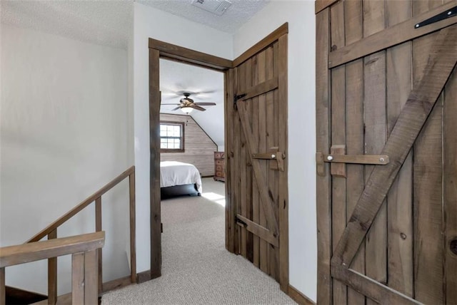 hallway with a textured ceiling and light carpet