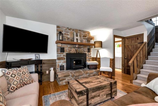 living room with a textured ceiling, light hardwood / wood-style flooring, and wooden walls