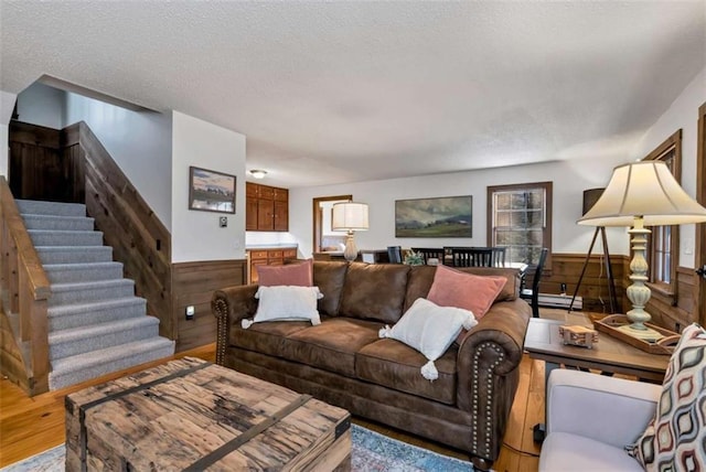 living room with hardwood / wood-style flooring, wood walls, and a textured ceiling