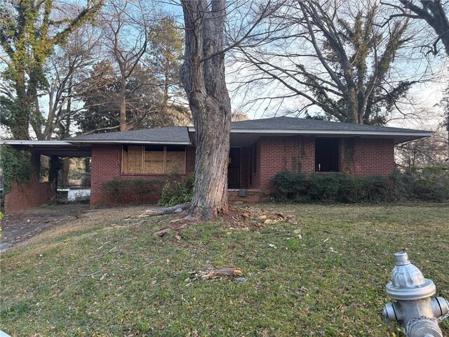 ranch-style house featuring a carport, brick siding, a front yard, and driveway