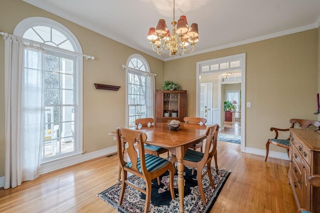 dining room featuring visible vents, baseboards, crown molding, light wood-type flooring, and a notable chandelier