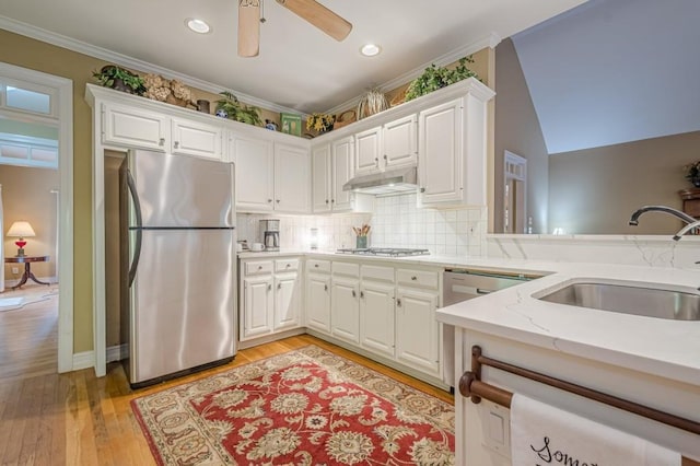 kitchen with backsplash, appliances with stainless steel finishes, white cabinetry, a sink, and under cabinet range hood