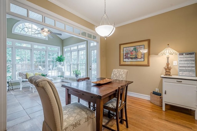 dining space featuring light wood-type flooring, ceiling fan, baseboards, and crown molding