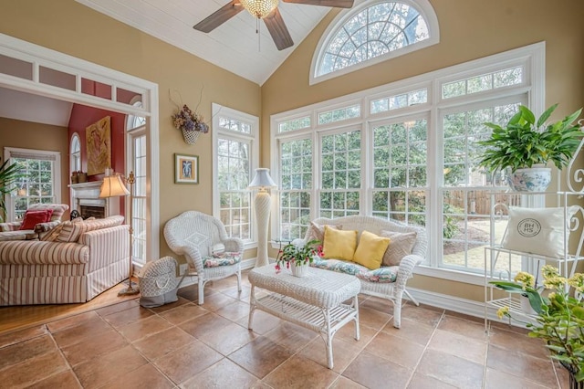 sunroom featuring vaulted ceiling, plenty of natural light, a fireplace, and a ceiling fan