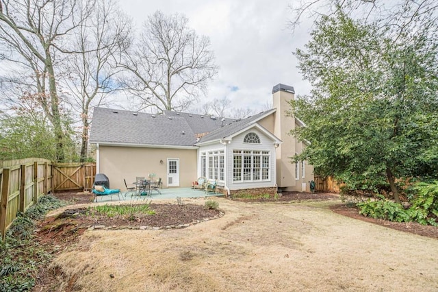 back of property with a patio, a chimney, stucco siding, a gate, and fence