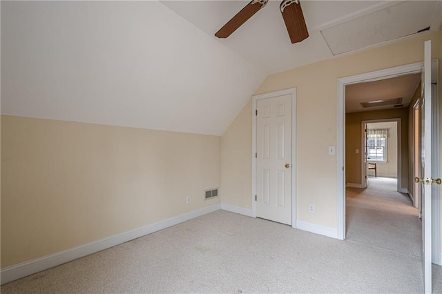 additional living space featuring lofted ceiling, light colored carpet, a ceiling fan, baseboards, and visible vents