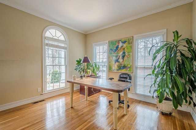 office space with light wood-type flooring, baseboards, visible vents, and crown molding