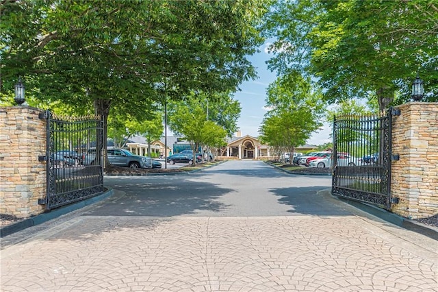 view of road with a gate, a gated entry, and curbs