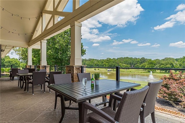 view of patio / terrace with outdoor dining area, a water view, and a balcony