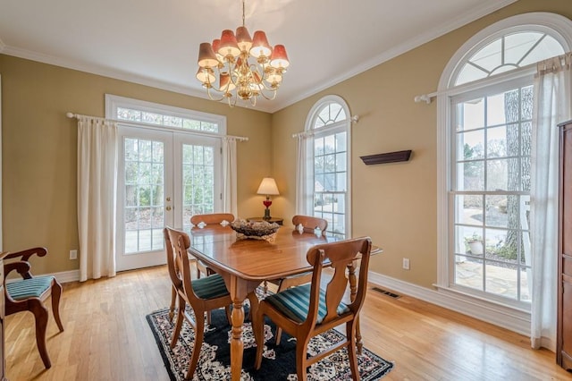 dining room with french doors, a notable chandelier, light wood-style flooring, ornamental molding, and baseboards