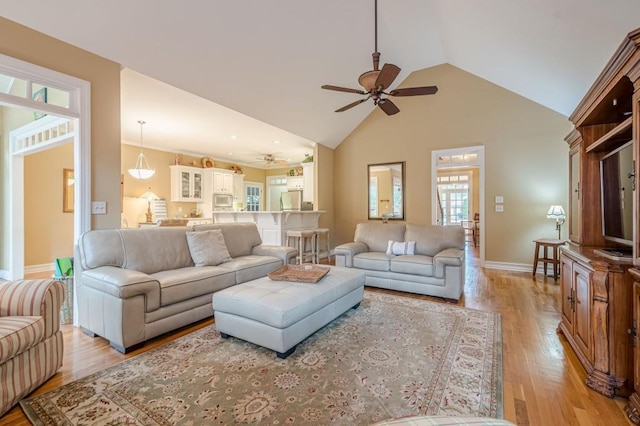 living room with high vaulted ceiling, light wood-style flooring, baseboards, and a ceiling fan