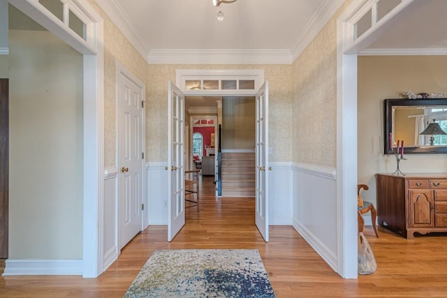 hallway featuring ornamental molding, wainscoting, light wood-style flooring, and wallpapered walls