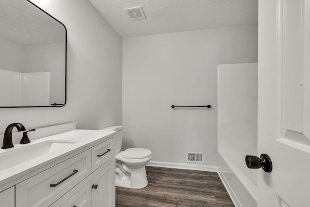 716 Phillips Dr, Monroe, GA 30656 - full bath with wood finished floors, toilet, a bath, vanity, and a textured ceiling