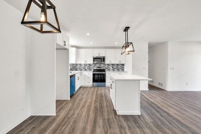 716 Phillips Dr, Monroe, GA 30656 - kitchen featuring appliances with stainless steel finishes, dark wood-style floors, a kitchen island, light countertops, and backsplash