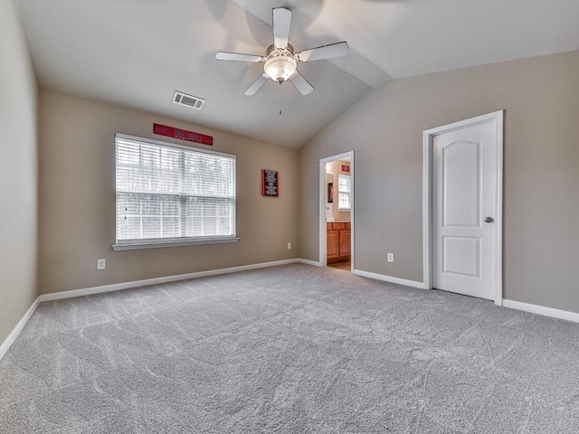 unfurnished bedroom featuring lofted ceiling, light colored carpet, visible vents, a ceiling fan, and baseboards