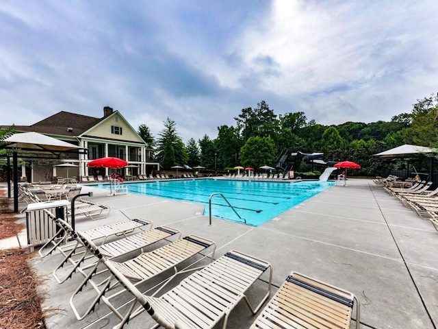 community pool with a patio area and a water slide