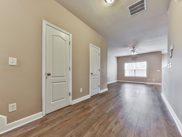 unfurnished room featuring baseboards, wood finished floors, visible vents, and a ceiling fan