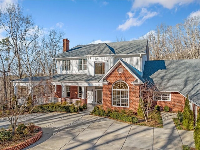 view of front of home featuring covered porch, brick siding, a chimney, and board and batten siding